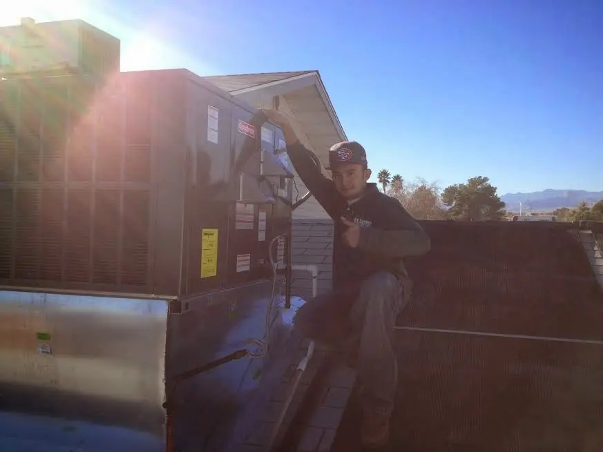 HVAC technician performing AC Tune-Up on a rooftop unit in Rosamond